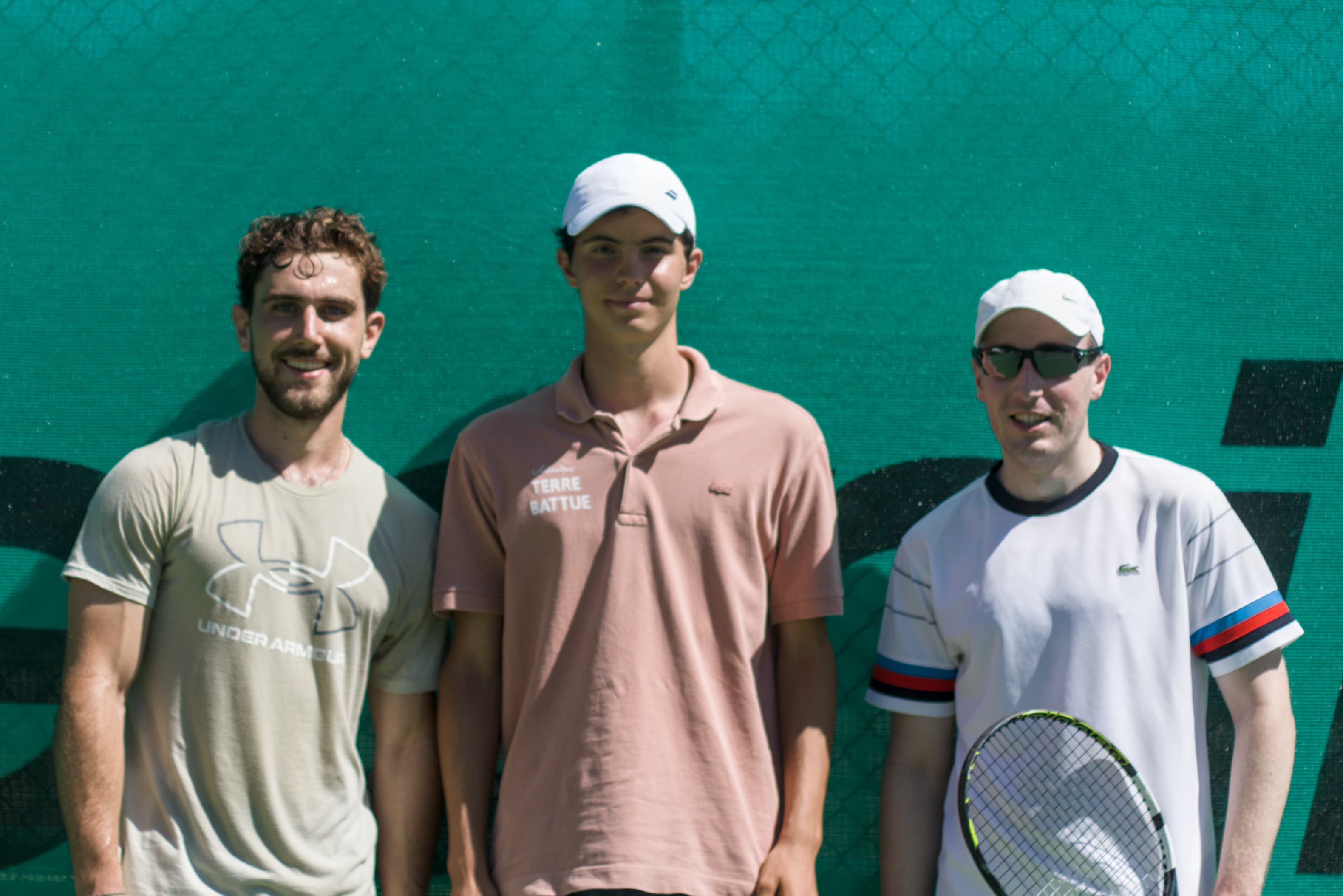 Trois joueurs posant devant la bannière